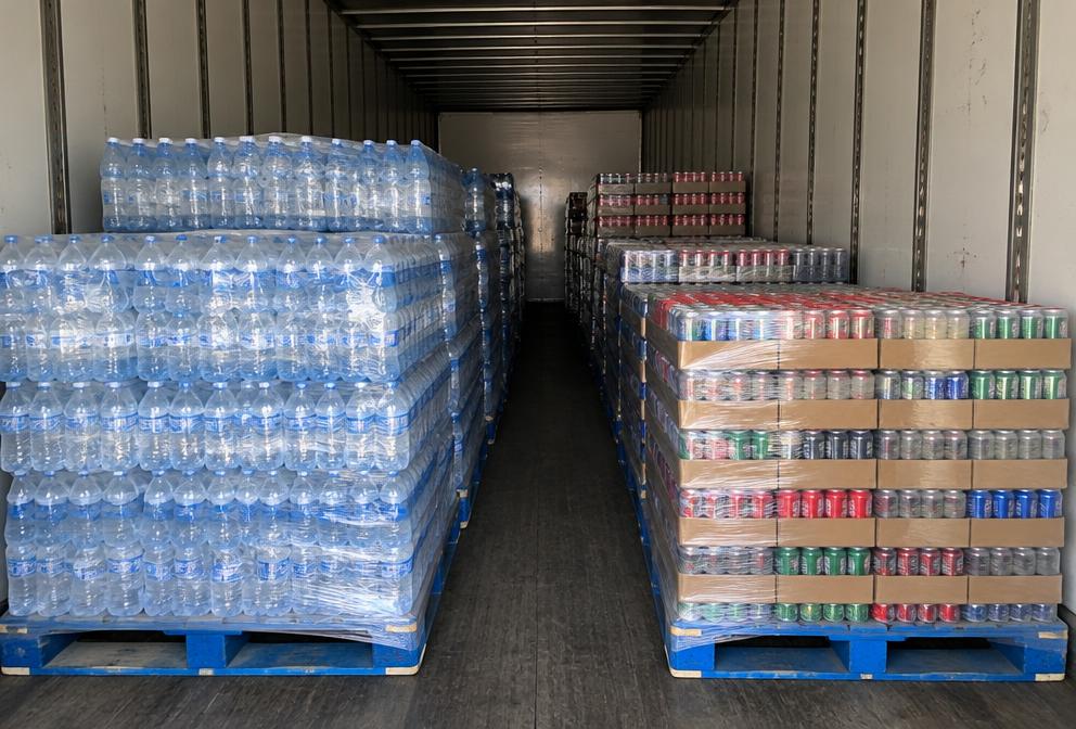 Pallets of bottled water and canned beverages inside a dry van trailer